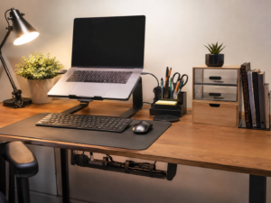 Mesa de trabalho organizada com notebook, luminária e porta-objetos sobre superfície limpa